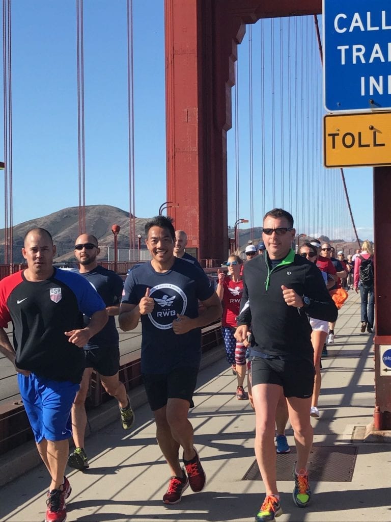 Runner on bridge smiling with thumbs up