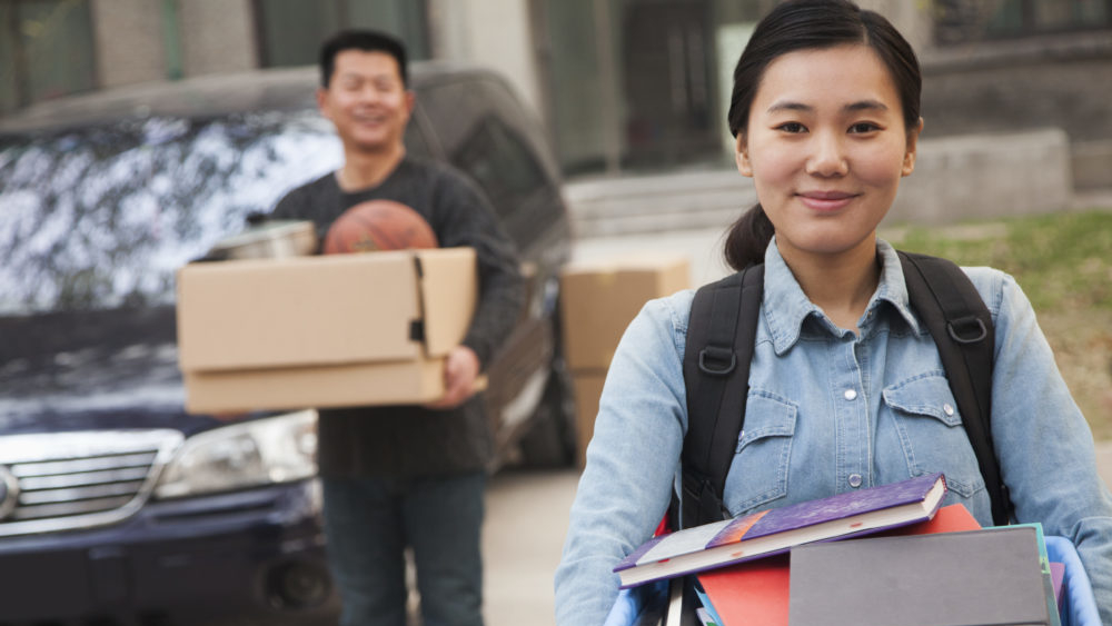 A student carries a box of books.