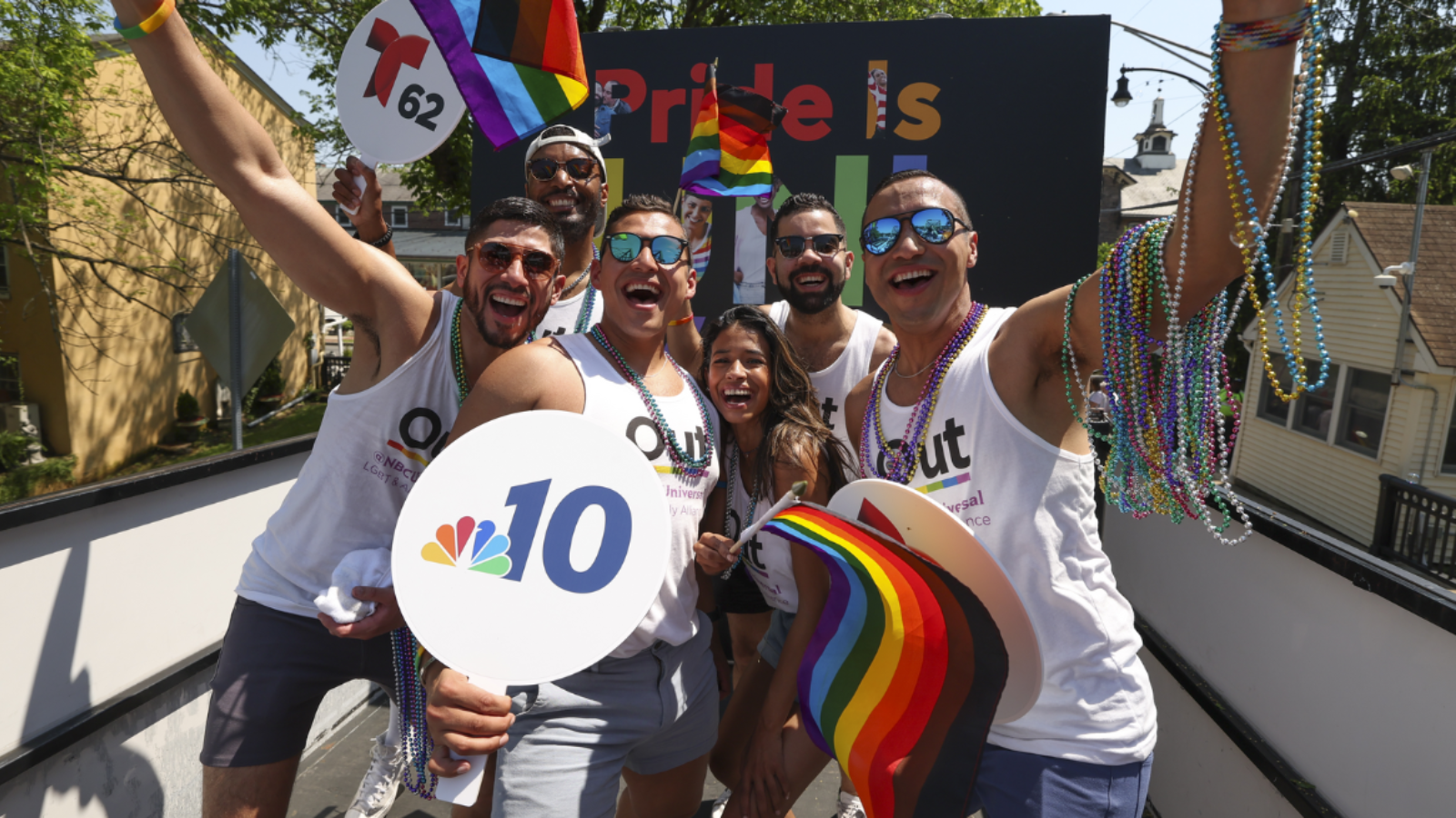 Comcast team members holding flags and fans during a Pride parade.