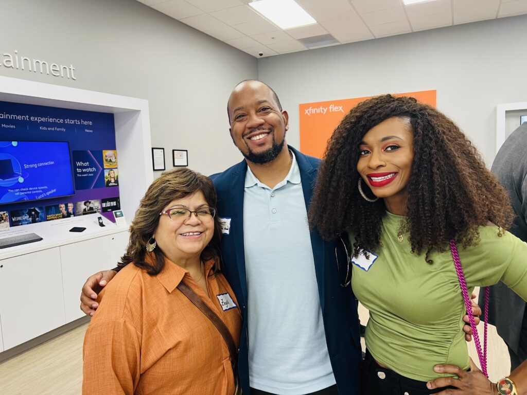 Three guests stand next to each other for a group photo at the Oakland Metro Chamber Mixer Reception at the Xfinity store on Broadway